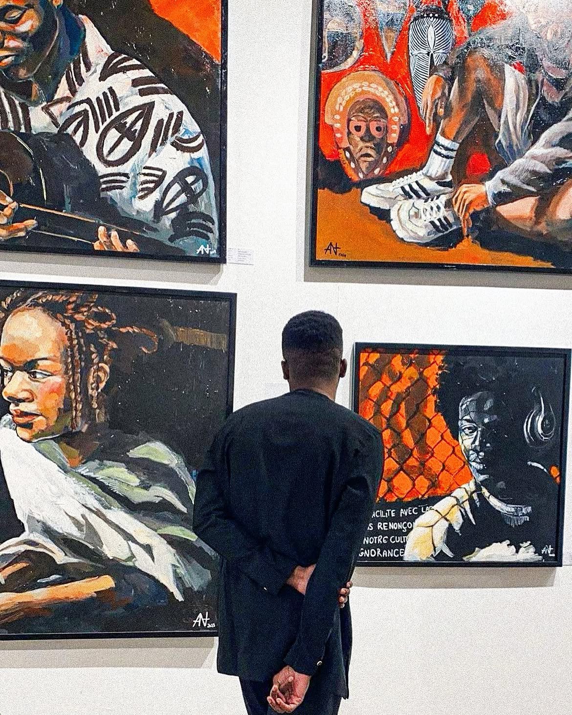 Mr. Yady de dos devant ses toiles lors d’une exposition